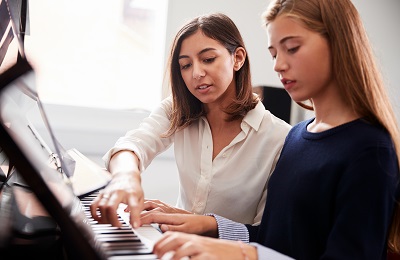 piano teacher and student sitting at a piano