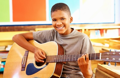 child with a smile holding a guitar